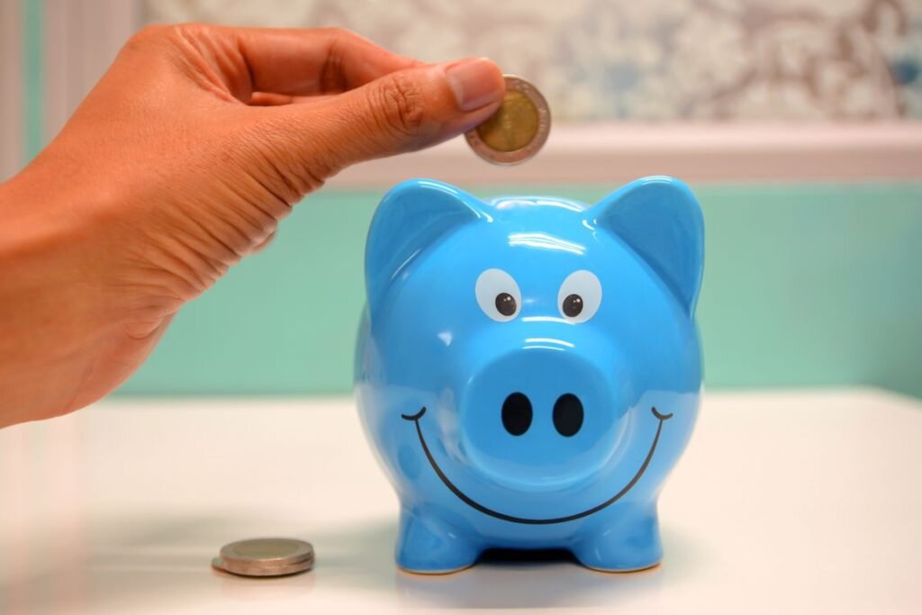 Hand inserting a coin into a piggy bank for emergency savings
