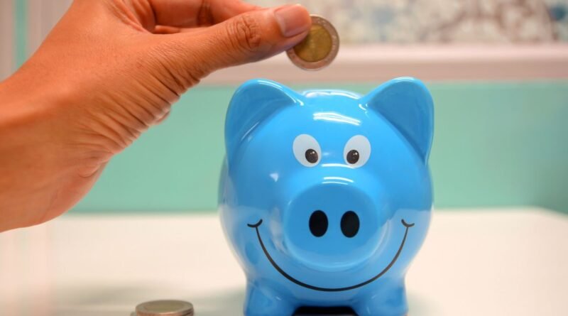 Hand inserting a coin into a piggy bank for emergency savings