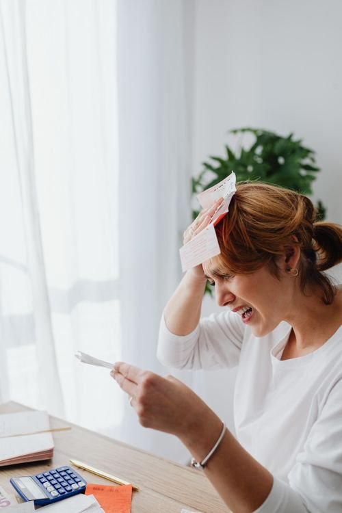 Woman sitting at a table stressed about bills in a bright living room