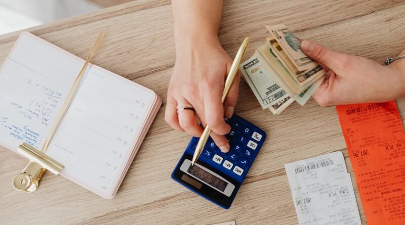 Person holding paper bills while using a calculator, representing decisions about old time-barred debt