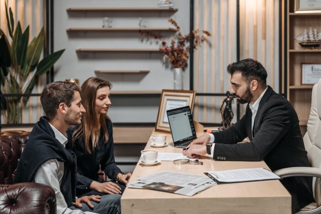Three professionals engaged in a business discussion at an office desk with a laptop