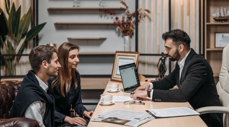 Three professionals engaged in a business discussion at an office desk with a laptop