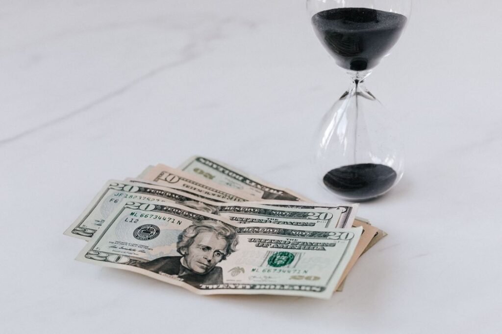 Hourglass beside a heap of US dollar bills, symbolizing time running out on old debt