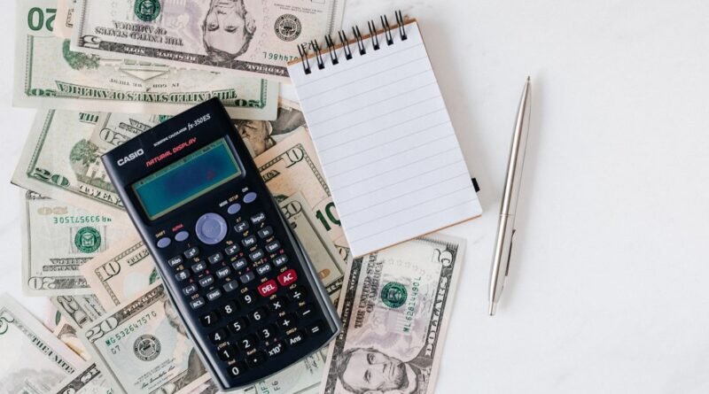Flat lay of US dollar bills with a calculator and notebook for budgeting
