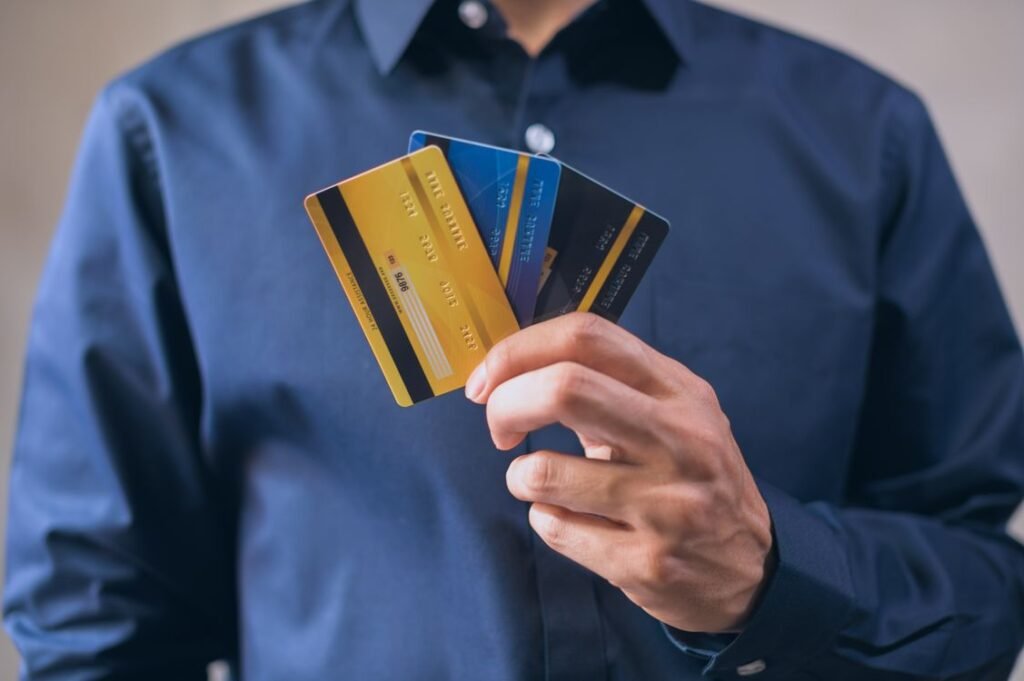 Man in a blue dress shirt holding three credit cards