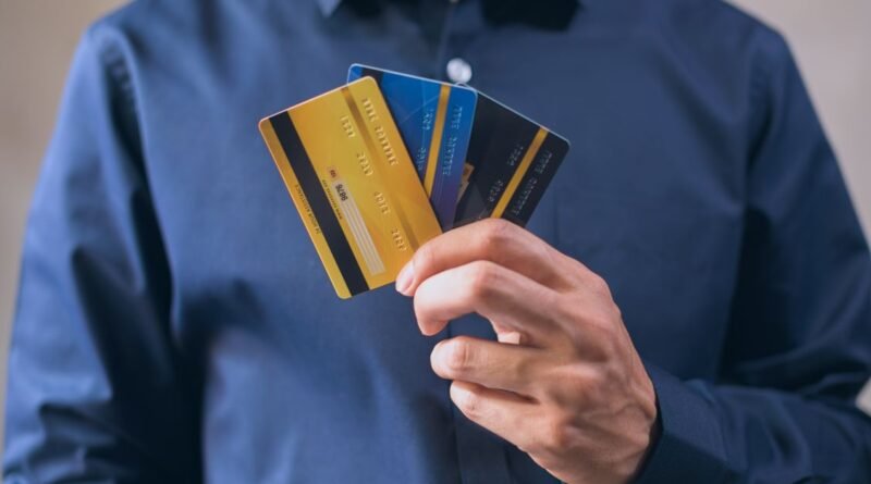 Man in a blue dress shirt holding three credit cards