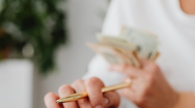 A woman using a calculator while holding cash, reviewing household bills at a desk