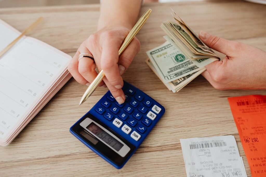 Person using a calculator with cash and receipts while planning a budget
