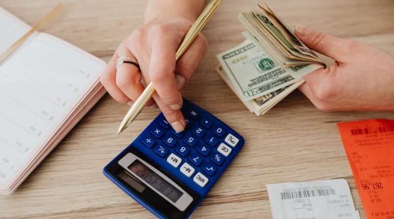 Person using a calculator with cash and receipts while planning a budget