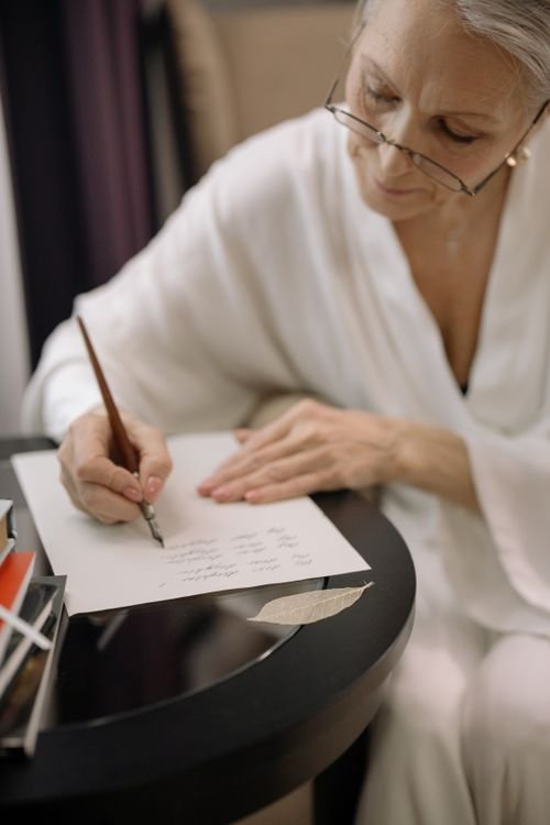 Senior woman writing a letter with a fountain pen at a desk