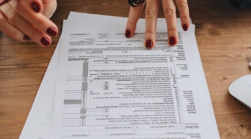 Hands examining tax forms on a wooden table