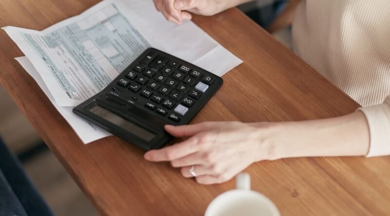Person using a calculator to plan finances and budget at a wooden desk