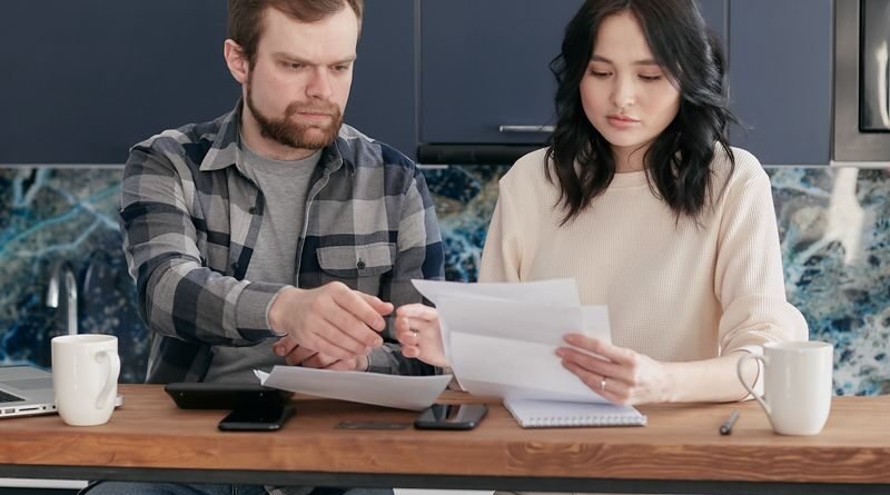 A young couple reviews bills and budget together in a modern kitchen