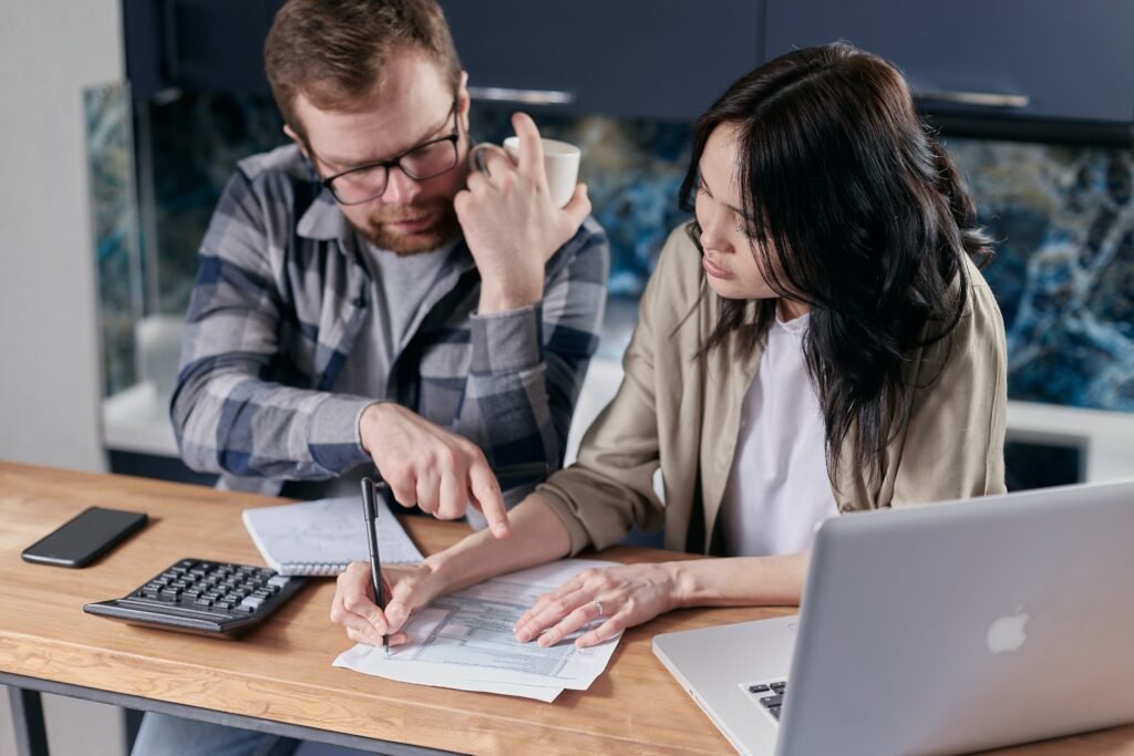 Couple reviewing and calculating household bills together at a desk with a calculator