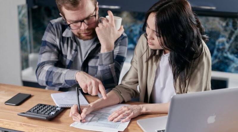 Couple reviewing and calculating household bills together at a desk with a calculator