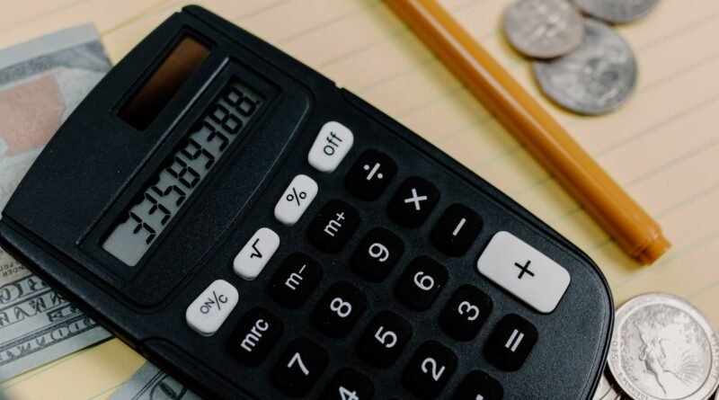 Calculator, cash, and coins on a desk representing the money at stake when evaluating debt relief offers