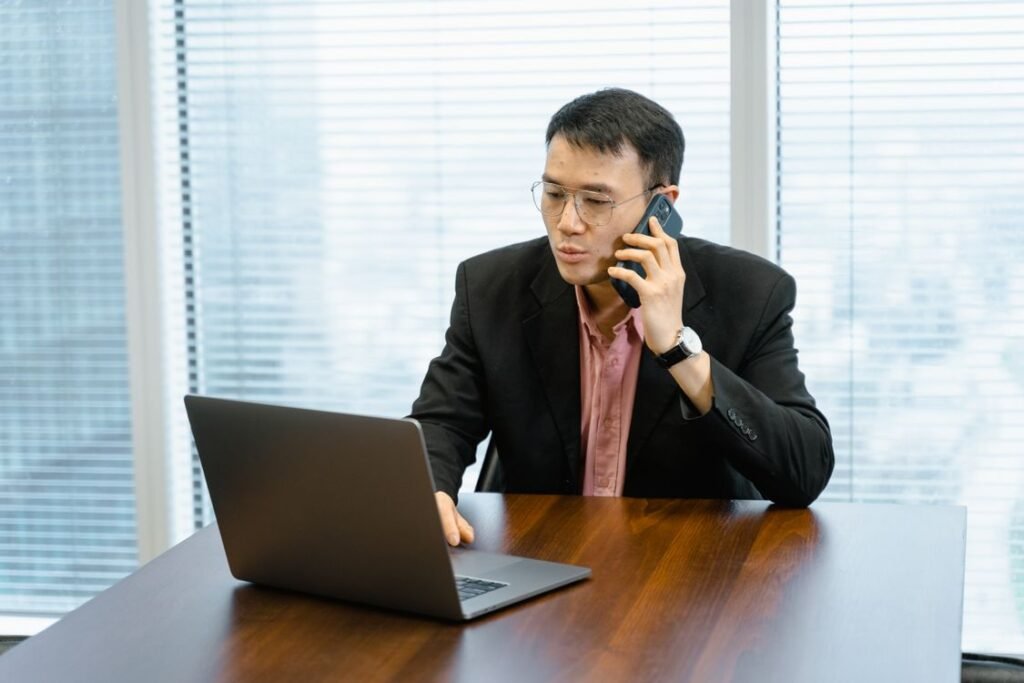 Businessman talking on the phone while working on a laptop in an office