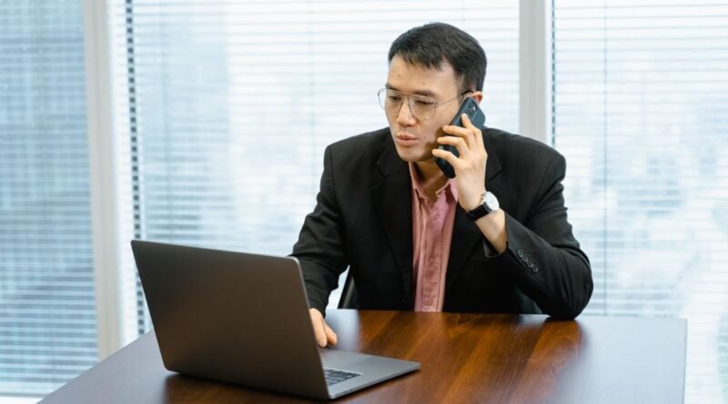 Businessman talking on the phone while working on a laptop in an office