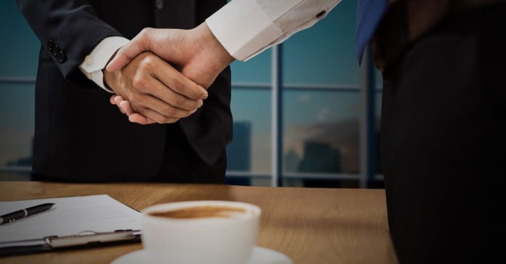 Two professionals shaking hands across a desk, representing a debt settlement agreement reached under federal fee rules