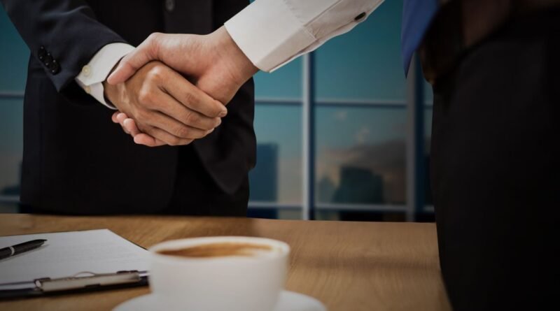 Two professionals shaking hands across a desk, representing a debt settlement agreement reached under federal fee rules