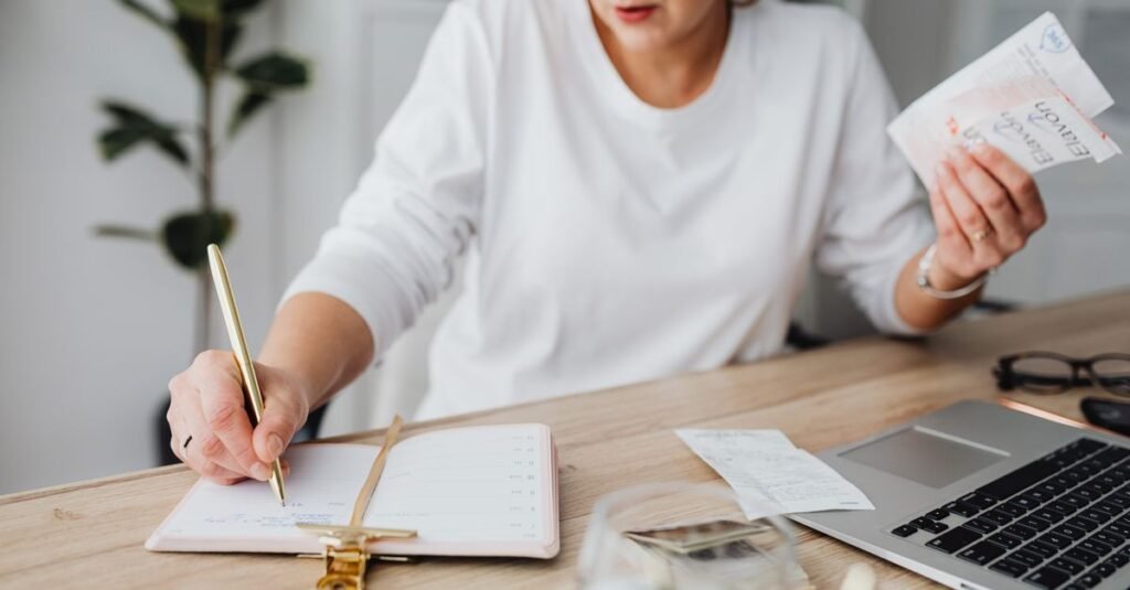 Person writing in a budget planner while reviewing finances
