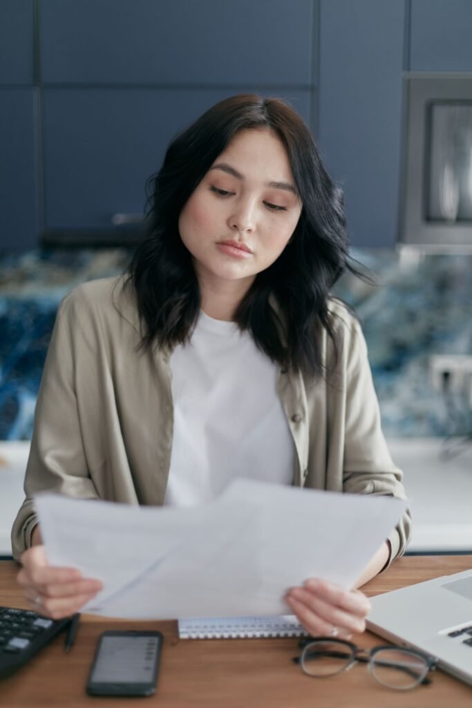 Woman carefully reading and analyzing financial documents at home