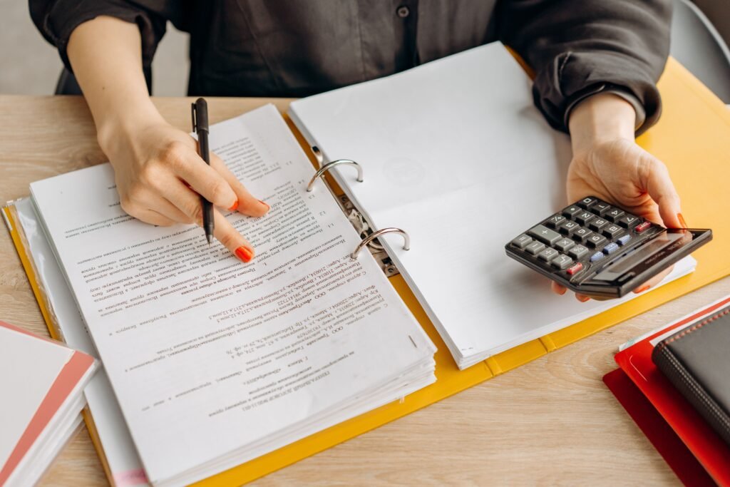 Woman reviewing financial documents and using a calculator on a wooden table, illustrating the bankruptcy means test income calculation