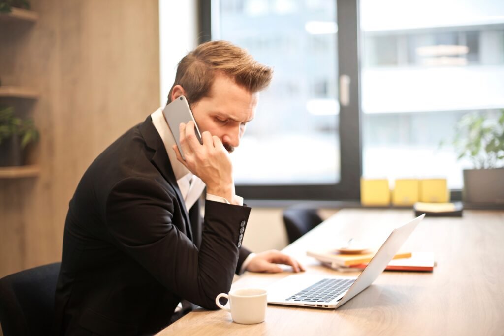 Man on a phone call in front of a laptop, illustrating how to stop debt collector calls
